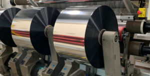 Three rolls of metalized packaging film (MOPP & MPET Films) on the cutting machine